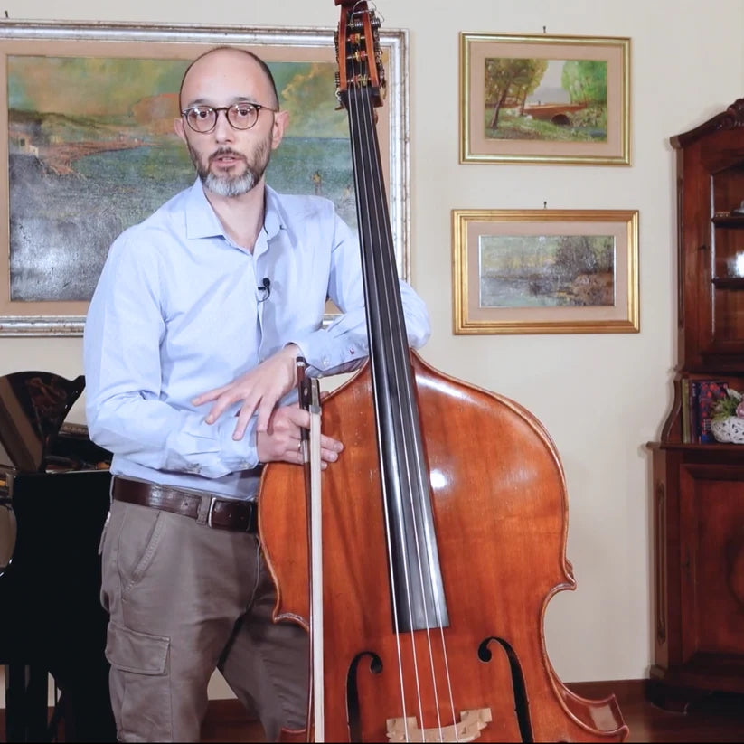 Christian Ciacco mid sentence holding a double bass with a French double bass bow in his hand.