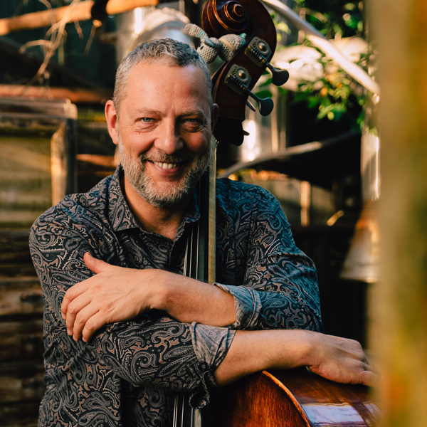 Cscab Pengo wearing a patterned shirt and hugging a double bass.