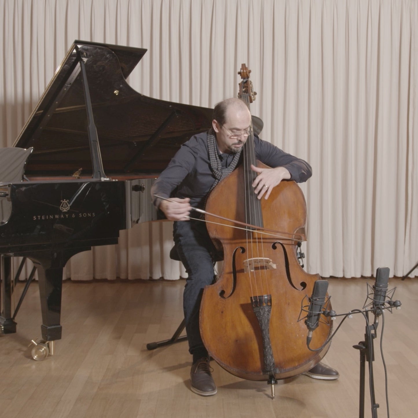 Petru Iuga playing a double bass with a German double bass bow in a studio.