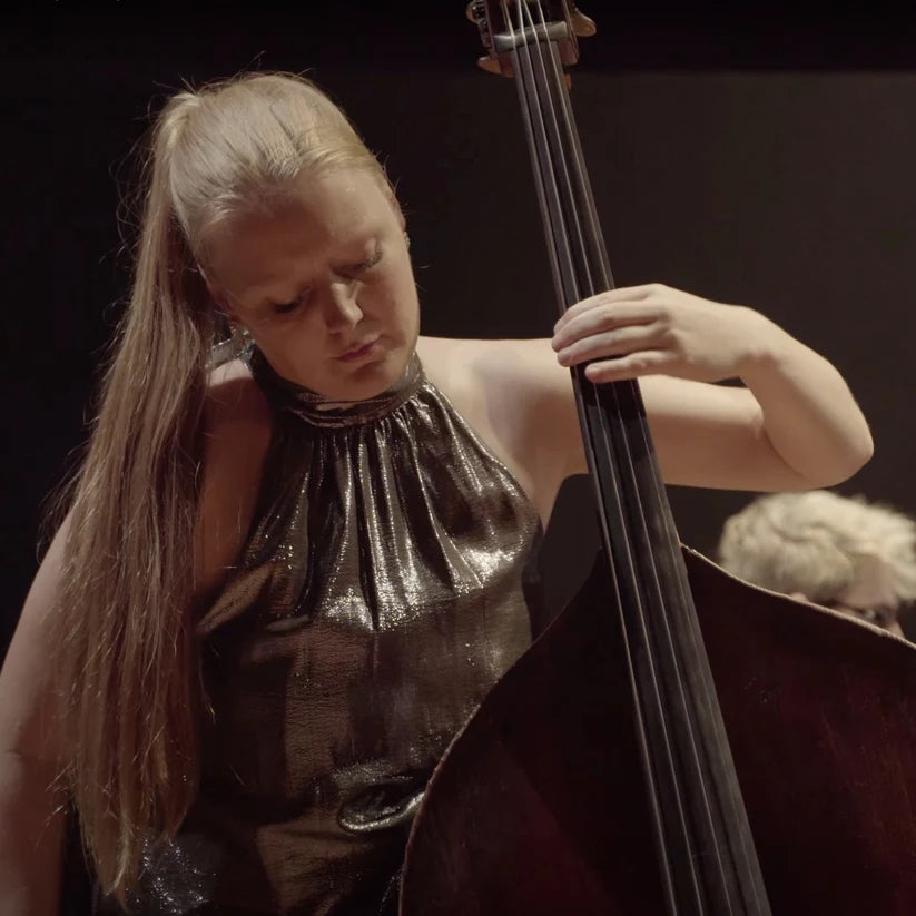 Phoebe Russell playing a double bass with a dark background.