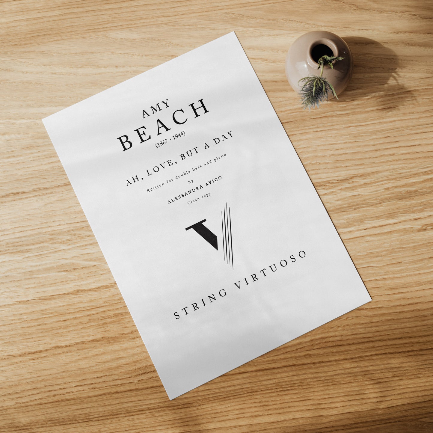 Sheet music of Amy Beach's Ah, Love but a day, edition for double bass and piano by Alessandra Avico. On a wooden table.