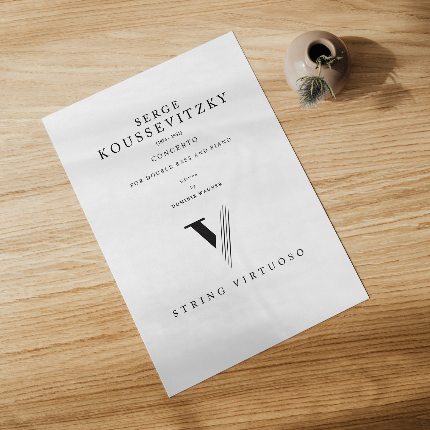 A printed sheet of music with the title 'Serge Koussevitzky Concerto' for double bass and piano, featuring the name 'Dominik Wagner' as the composer. The sheet music is placed on a wooden surface with a decorative item to the side.