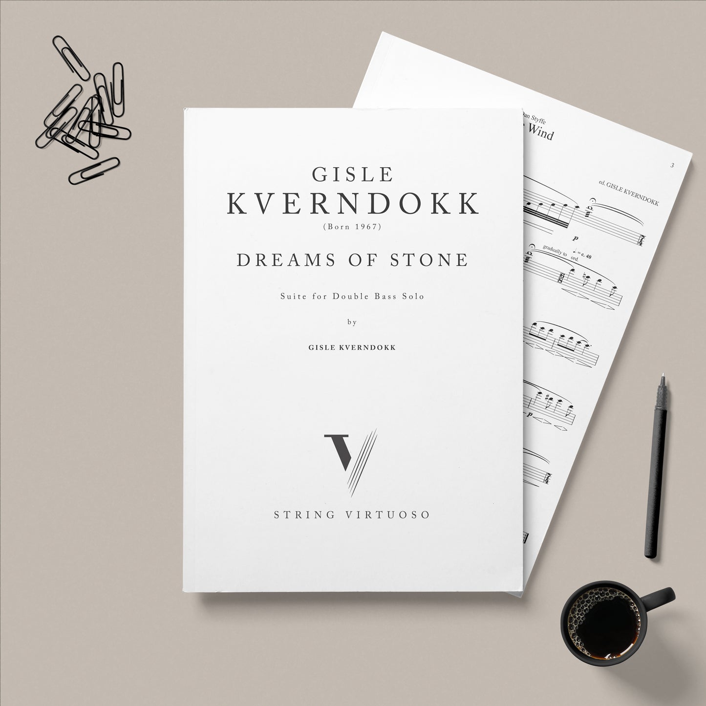 PDF sheet music titled 'Gisle Kverndokk - Dreams Of Stone' suite for double bass solo, displayed on a table alongside paper clips, a pen, and a coffee cup.