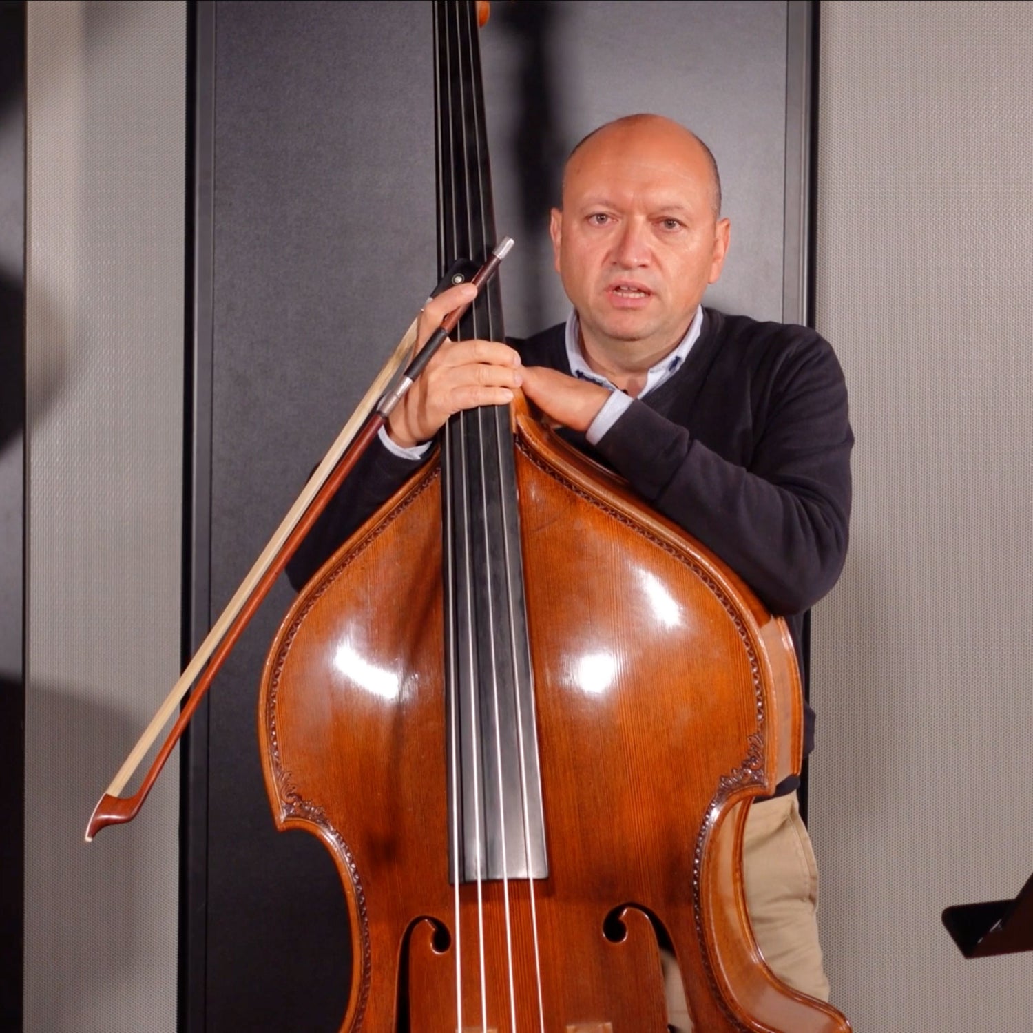 Davide Botto in a grey sweater holding a double bass.