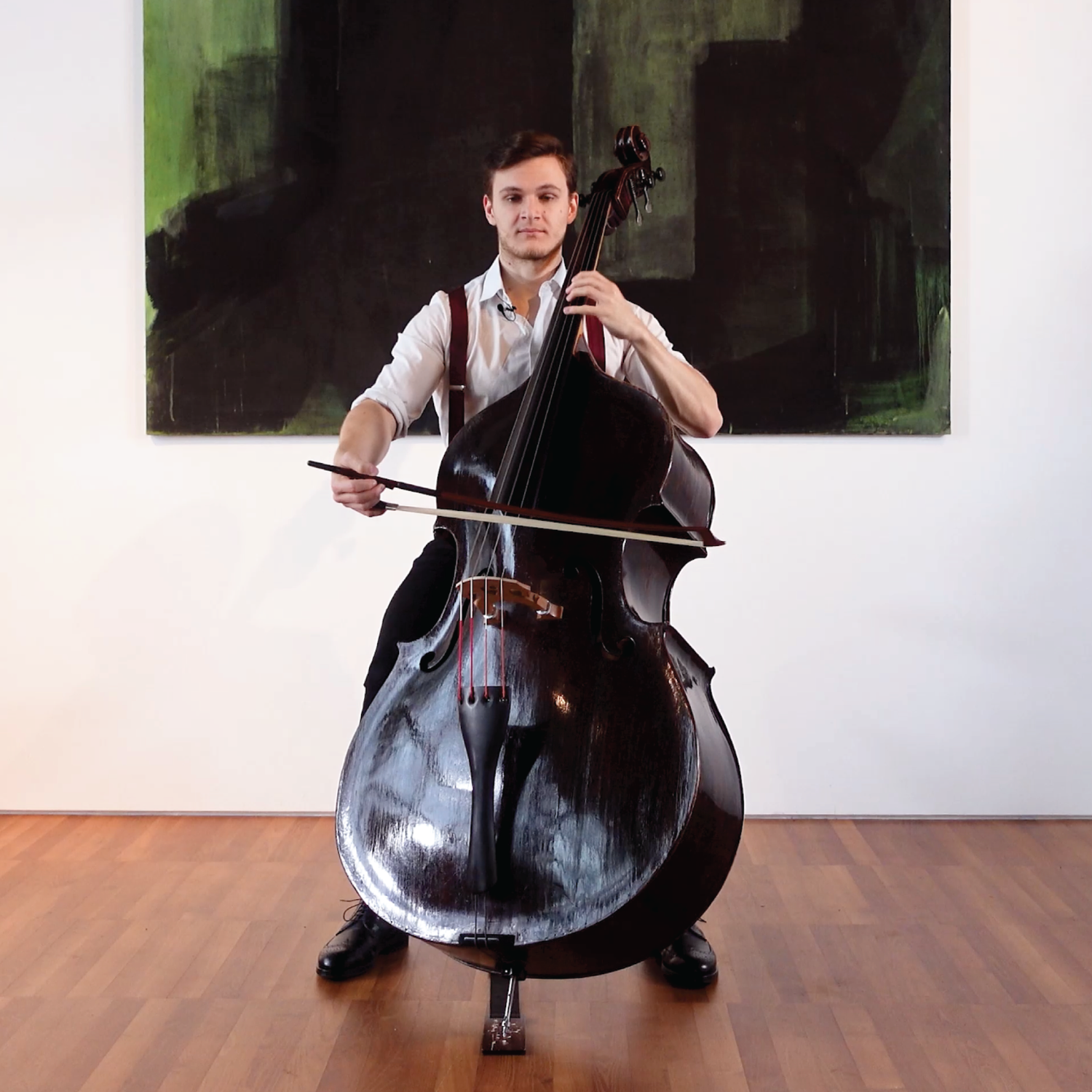 Dominik Wagner playing a double bass in front of a painting, recording the performance for a video course.